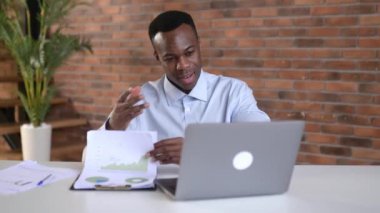 Odaklanmış Afro-Amerikan iş adamı finansal grafikleri, karı, iş yerinde oturmayı analiz ediyor. Zeki siyah erkek öğrenci çevrimiçi ders çalışıyor, çevrimiçi konferans dinliyor, serbest çalışan bilgisayar kullanıyor.