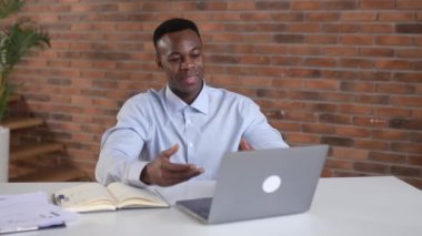 Remote conversation. African american successful business man, ceo company, sales manager, uses laptop for distant communication with client, sits in modern office, gesturing with his hands, smiling