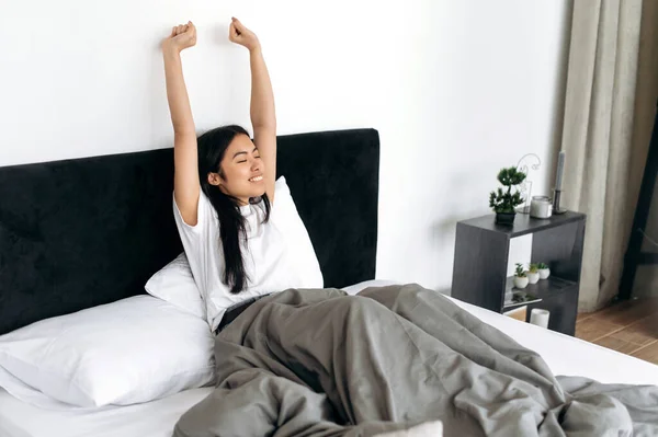 티셔츠를 아시아인 여자가 웃으며 깨어나서 침대에 후팔을 기분좋게 하루를 시작하며 — 스톡 사진