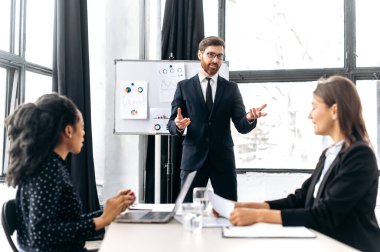 Nüfuzlu Kafkas çekici erkek patron, grup beyin fırtınası yapıyor, yeni bir iş projesi için fikirler tartışıyor, kadın ortaklarına bir iş planı sunumu yapıyor. Takım çalışması, işbirliği