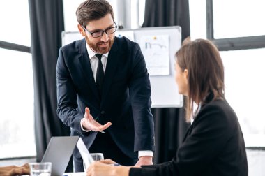 İki iş arkadaşının sohbeti. Başarılı iş arkadaşları, Kafkas erkek ve kadın, modern bir ofiste, yeni bir proje, finansal bir iş planı, gelecekteki stratejiyi tartışıyorlar.