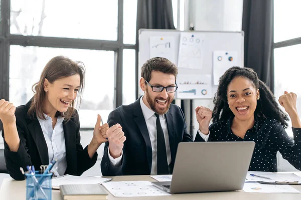 Neşeli yaratıcı iş ekibi birlikte çalışıyor. Çok ırklı meslektaşlar birlikte strateji üzerinde kafa patlatıyorlar, modern ofiste oturuyorlar, dizüstü bilgisayar kullanıyorlar, iyi bir anlaşma yapıyorlar, kar ediyorlar, gülümsüyorlar, el kol hareketi yapıyorlar.