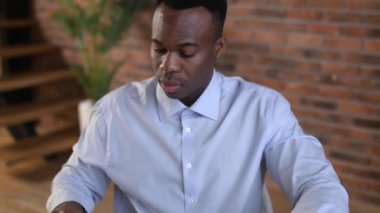 Odaklanmış Afro-Amerikan iş adamı finansal grafikleri, karı, iş yerinde oturmayı analiz ediyor. Akıllı siyah erkek dizüstü bilgisayar kullanıyor, konsantre çalışma mali raporlar, planlama iş planı, strateji