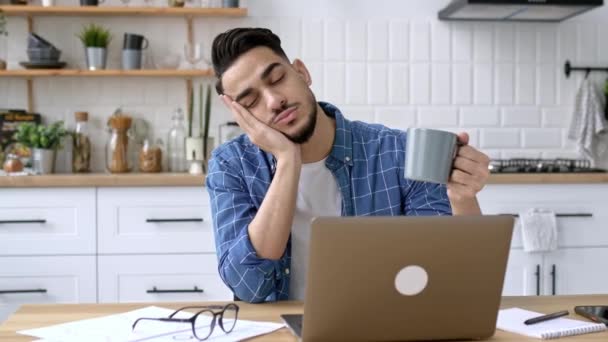 疲惫的印度人或阿拉伯人 自由职业者 设计师 远离家乡工作 厌倦了网上无聊的工作 长期疲乏或过度劳累 手里拿着一杯咖啡 睡着了 — 图库视频影像