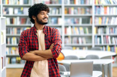 Yakışıklı kıvırcık saçlı, Hintli ya da Arap asıllı serbest çalışan ya da öğrenci, şık modern giysiler içinde, kütüphanede duruyor, kollarını kavuşturup, başka tarafa bakıyor, gülümsüyor, arkadaşça düşünüyor, hayal kuruyor.