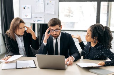 Stresli çalışma ortamı. Meslektaşlar, projeden elde edilen kârdan kaynaklanan zarara bağlı olarak, olumsuz duygular yaşayan, ofisteki masaüstünde konuşan bilgilerle kafalarını karıştırıyor.