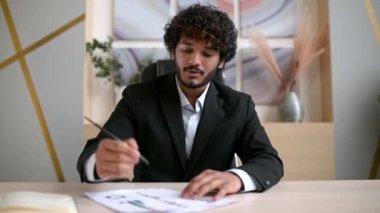 Zeki kıvırcık saçlı, kıvırcık saçlı Hintli iş adamı, finansal danışman, şirket yöneticisi konferans görüşmesinde iş arkadaşı ya da müşteriyle konuş, sanal toplantı, beyin fırtınası, belgeler, kameraya bak