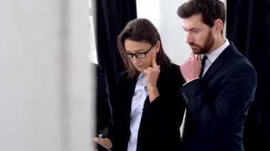 Collaboration concept. Successful elegant multiracial people, business partners, are standing in modern office, discussing the project, predicting its success, discussing new ideas, smiling