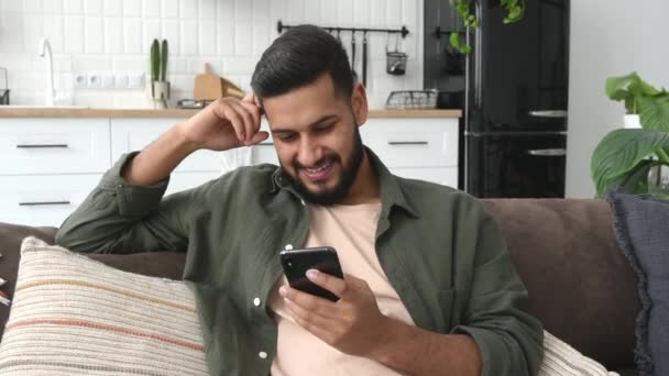 Positive Indian Arabian Attractive Guy Using His Smartphone While Sits — Vídeo de Stock