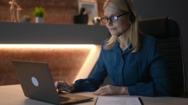 Work after the end of the working day. Responsible tired adult caucasian female company owner, manager, working in the office in the evening time, finishing work on the project. Overwork, deadline