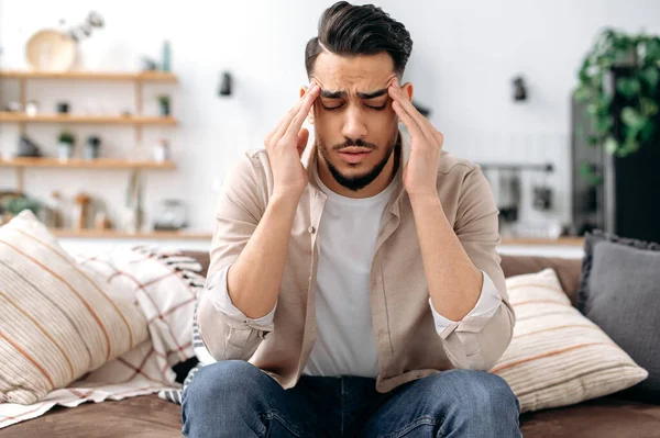 Headache Migraine Concept Sad Indian Arabian Man Sitting Home Sofa — Stockfoto