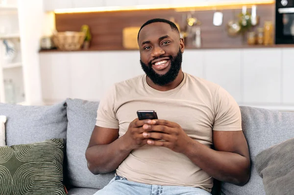 Handsome Positive African American Man Casual Wear Sits Home Sofa — Fotografia de Stock