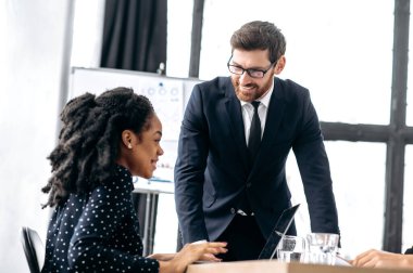 Negotiations of two intelligent coworkers. Successful business colleagues, caucasian man and african american woman, in modern office, discussing new project, financial business plan, future strategy