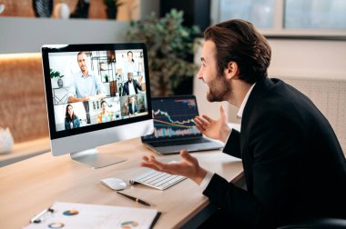 Successful caucasian male stock broker sits in his modern office, talking by a video conference with colleagues, working out a crypto strategy, discussing risks. Group brainstorm by video call