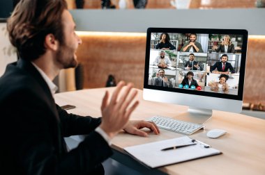 Intelligent business man, sit in office, conducts a brainstorm with multiracial business team, discussing financial strategy and analyzing risks. Communication by video conference, financial briefing