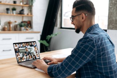 Smart indian or arabian guy meet with a group of multiracial colleagues gathered in a video conference to communicate and discuss work issues and new project, planning business plan. Group brainstorm