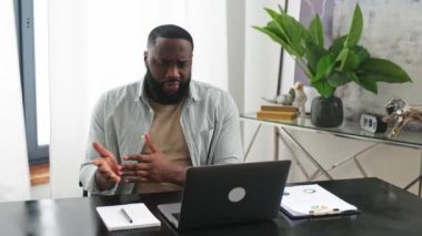 Online video conference, briefing. Successful friendly confident african american man, owner company, sales manager, sit in office, has business conversation with colleagues by video call using laptop