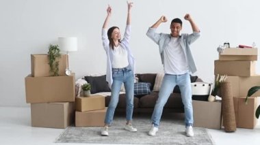 A loving young couple rejoices in their new home. Happy married couple in love dancing in living room, they moved to a new apartment, next to cardboard boxes with things. Real estate investment