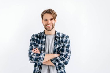 Portrait of a positive attractive confident blue-eyed caucasian stylish man standing on a white isolated background with crossed arms, looking at the camera, smiling friendly