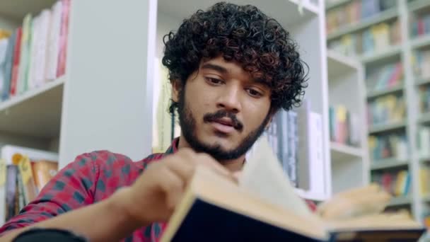 Handsome Attractive Focused Indian Arabian Student Guy Sits Library Bookshelf — Vídeo de stock