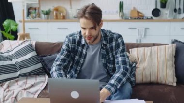 Relaxation at home. Satisfied positive calm caucasian man, freelancer, finished online work, resting after a working day, sits on a sofa, throwing his hands behind his head, looking away, smiling