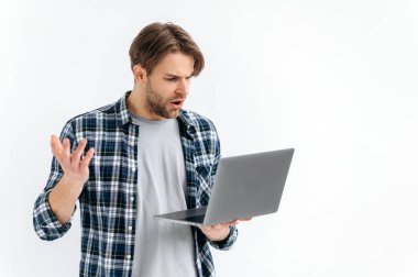 Beyazların izole edilmiş arka planda duran kafası karışmış, beyaz şaşkın, beyaz bir beyaz adam, elinde bir dizüstü bilgisayar tutuyor, ekrana şaşkın bakıyor, beklenmedik haberler görüyor, mesaj, elle hareket ediyor.