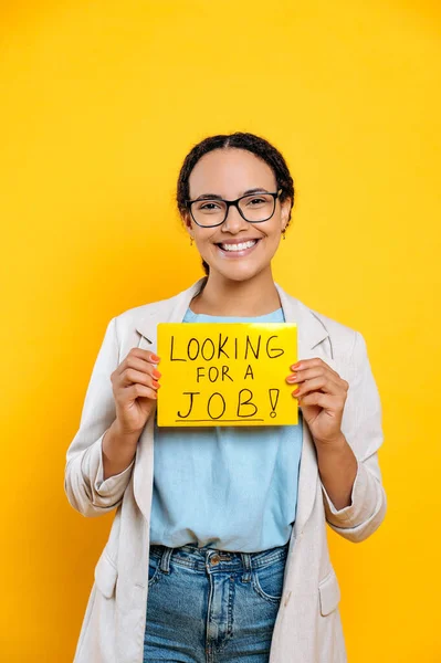 正面的成功的聪明的男女混血的年轻女性 寻找工作的创意专家 站在孤立的橙色背景上 展示一个寻找工作的标志 看着相机 — 图库照片