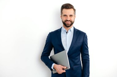 Pozitif başarılı beyaz sakallı bir iş adamının portresi takım elbiseli, seo, danışman, broker, izole edilmiş beyaz arka planda duruyor, dizüstü bilgisayarı tutuyor, kameraya bakıyor, arkadaşça gülümsüyor.