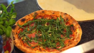 Şef İtalyan usulü kızarmış pizzayı roka ile süslüyor.