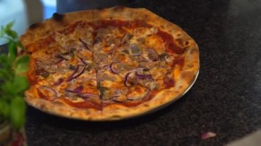 Şef pizzanın üzerine zeytinyağı döker ve tasarım için yeşillikleri ortaya serer.