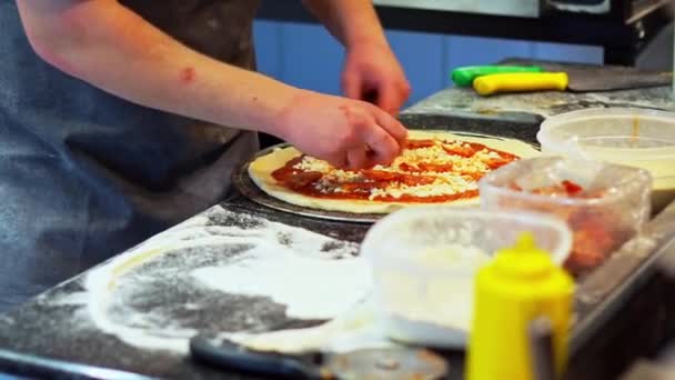 Kuchař utváří těsto na pizzu, rozprostře ho na kovový pekařský plech a rozloží ingredience — Stock video
