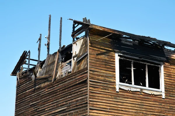 A ruína carbonizada e restos de uma casa incendiada — Fotografia de Stock