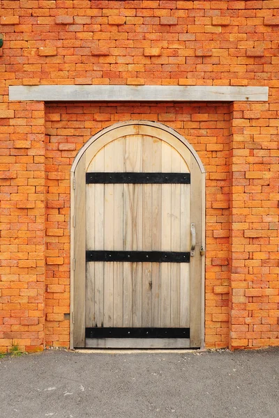 Porta de madeira na parede de tijolo laranja — Fotografia de Stock