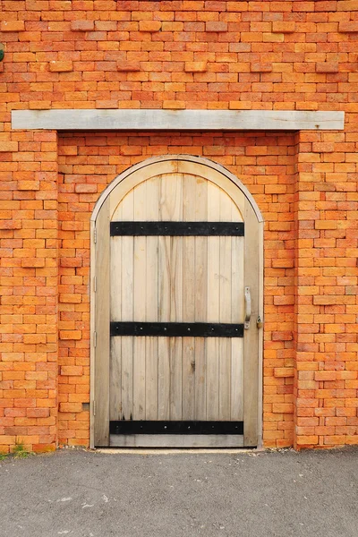 Holztür an orangefarbener Ziegelwand — Stockfoto