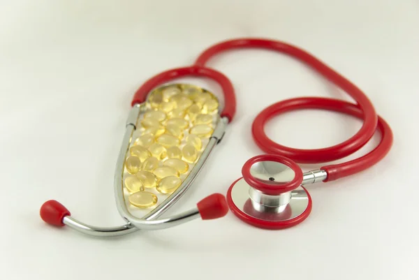 Omega 3 capsules with red stethoscope — Stock Photo, Image