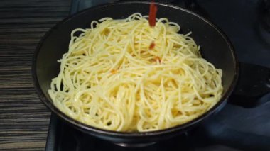 Kızartma tavasında sebzeli spagetti pişirip karıştırıyorum.
