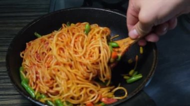 Kızartma tavasında sebzeli spagetti pişirip karıştırıyorum.