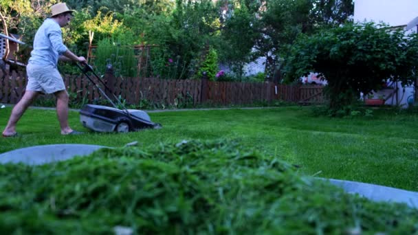 ティーン男切断草とともに電動芝刈り機で庭 — ストック動画