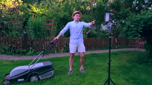 芝刈り機を持っている若い男は彼の人生をオンラインで持っている 自宅で働く — ストック動画