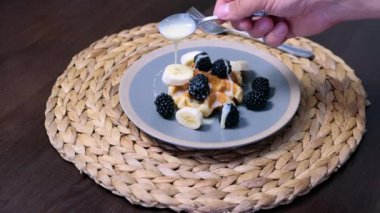 Milk syrup on belgian waffles served with blackberries. Sweet breakfast or dessert closeup view. High quality 4k footage