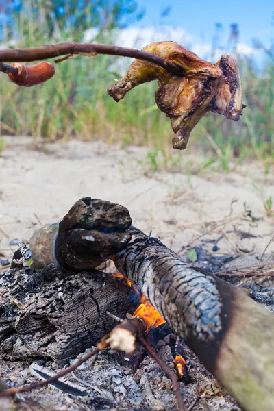 Rostning kycklingkött och korv på lägereld — Stockfoto