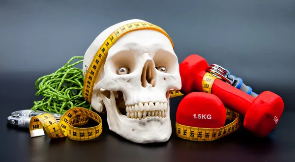 Fitnessausrüstung und menschlicher Schädel — Stockfoto