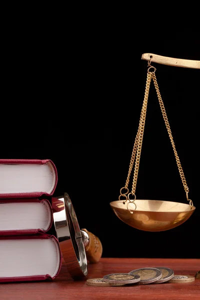 Wetboeken, geld, Vergrootglas en schalen van Justitie — Stockfoto