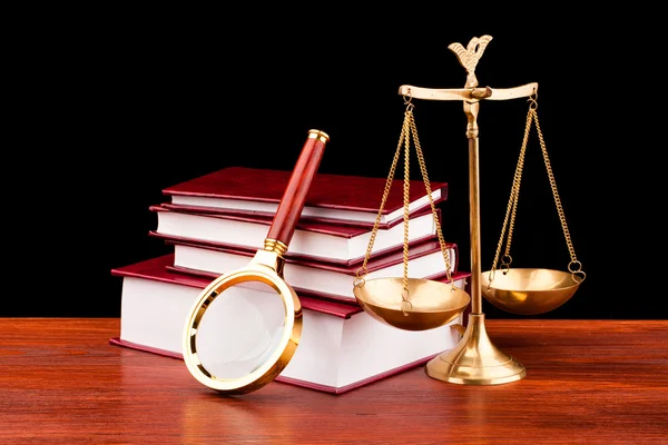 Books of justice and magnifying glass — Stock Photo, Image