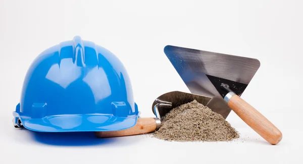 Hardhat azul, pilha de areia e espátula de pedreiro — Fotografia de Stock