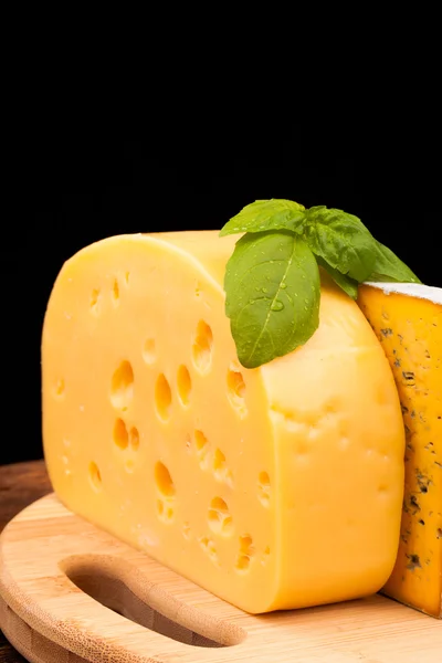 Various types of cheese and tomato on wooden table isolated on black — Stock Photo, Image