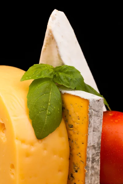 Various types of cheese and tomato on wooden table isolated on black — Stock Photo, Image