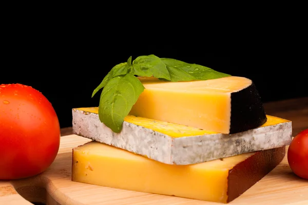 Olika typer av ost och tomat på träbord isolerade på svart — Stockfoto