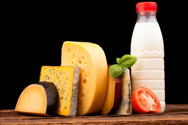 Various types of cheese and milk isolated on black — Stock Photo, Image