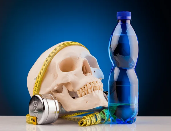 Menselijke schedel en fitness halters en fles water — Stockfoto